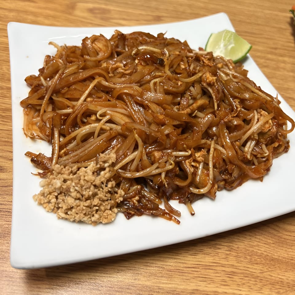 Mercy Thai Restaurant's Pad See Ew, a plate of stir-fried noodles with a lime wedge.
