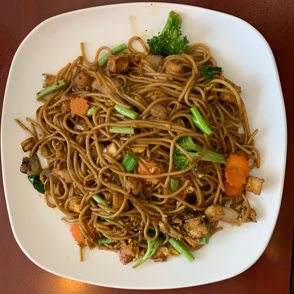 Mercy Thai Restaurant's Pad See Ew with wide noodles, broccoli, carrots, and tofu on a white plate.