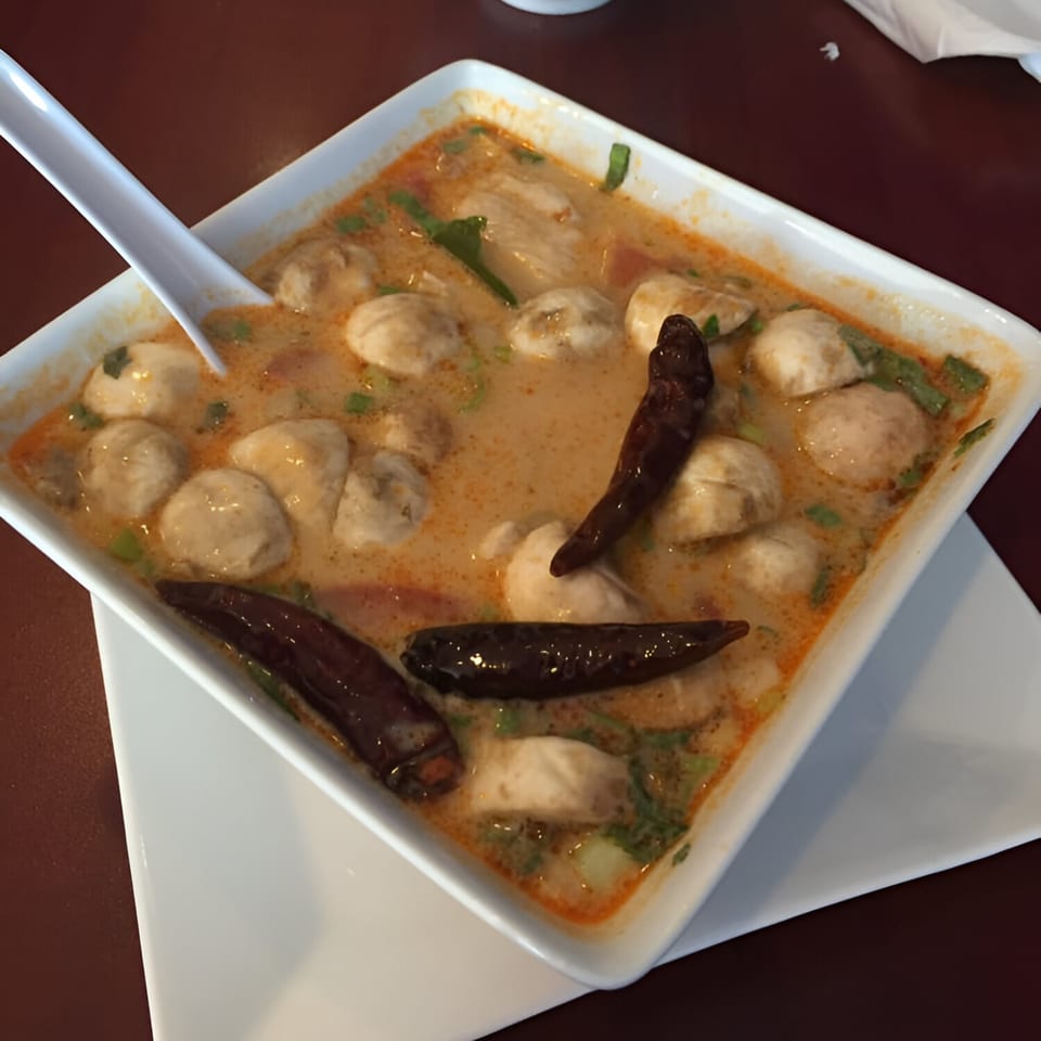 Mercy Thai Restaurant's spicy Tom Yum soup with meatballs, garnished with dried red chilies and cilantro.